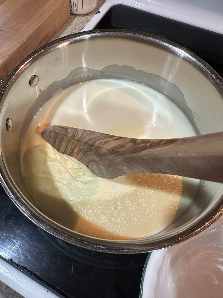 removing raw milk film wwith a wooden spoon in pot