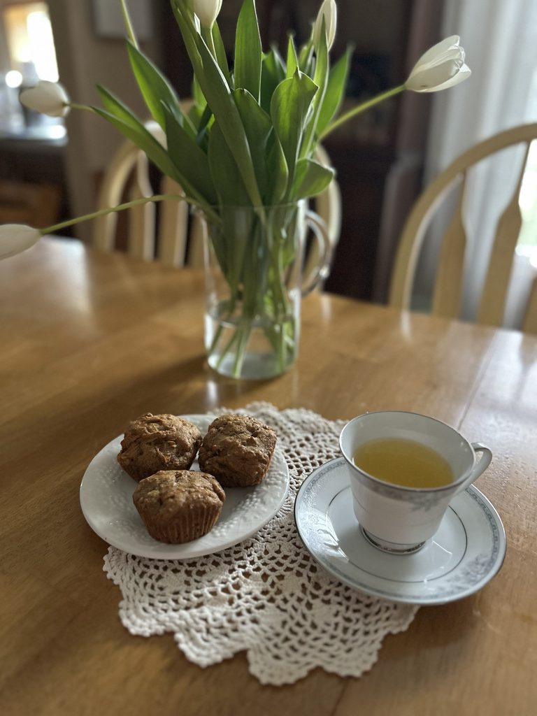 Freshly-Milled Whole Wheat Carrot Cake Muffins sitting on a plate next to a tea cup