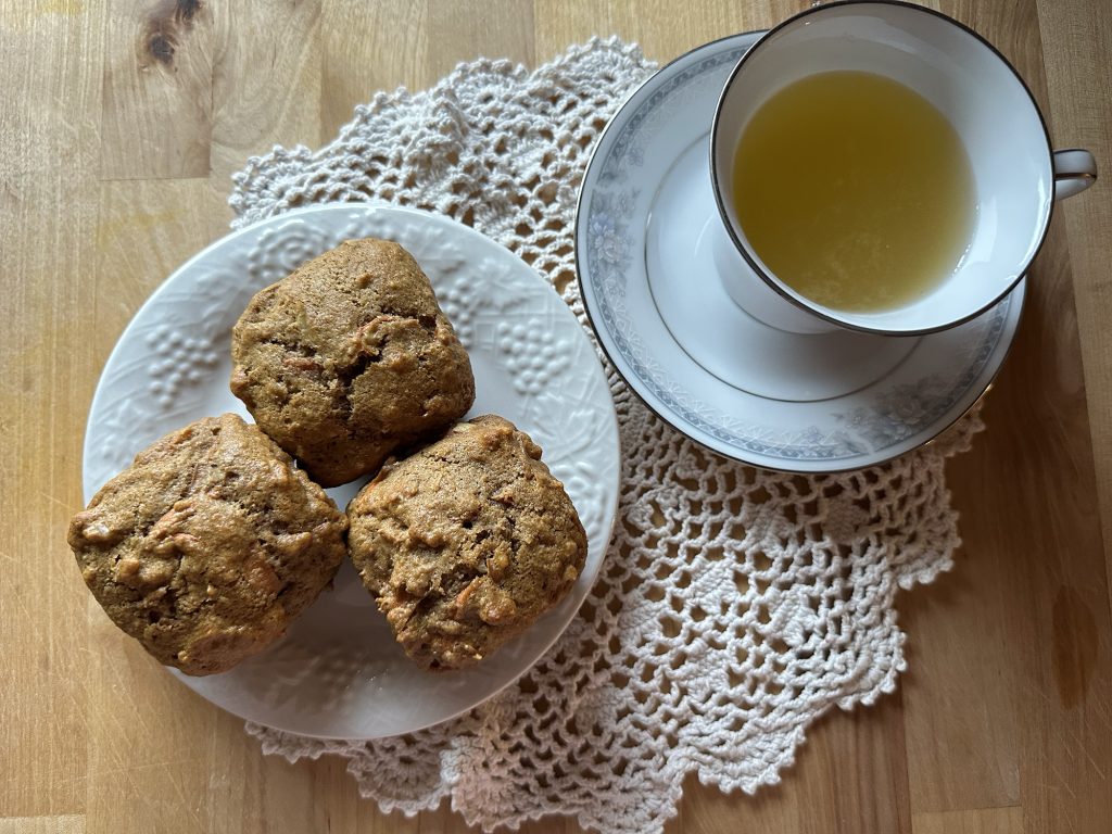 Freshly-Milled Whole Wheat Carrot Cake Muffins sitting on a plate next to vintage tea cup