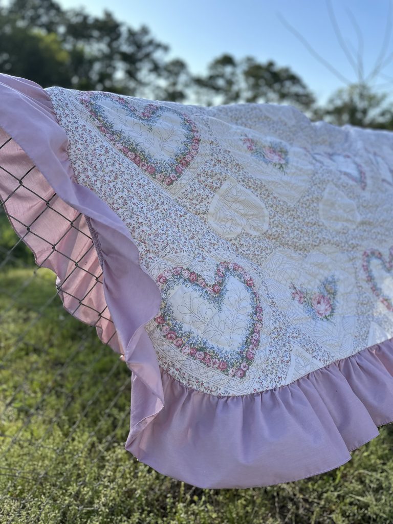 Pink heart quilt sitting on a fence blowing in the wind for simple spring thrifted decor