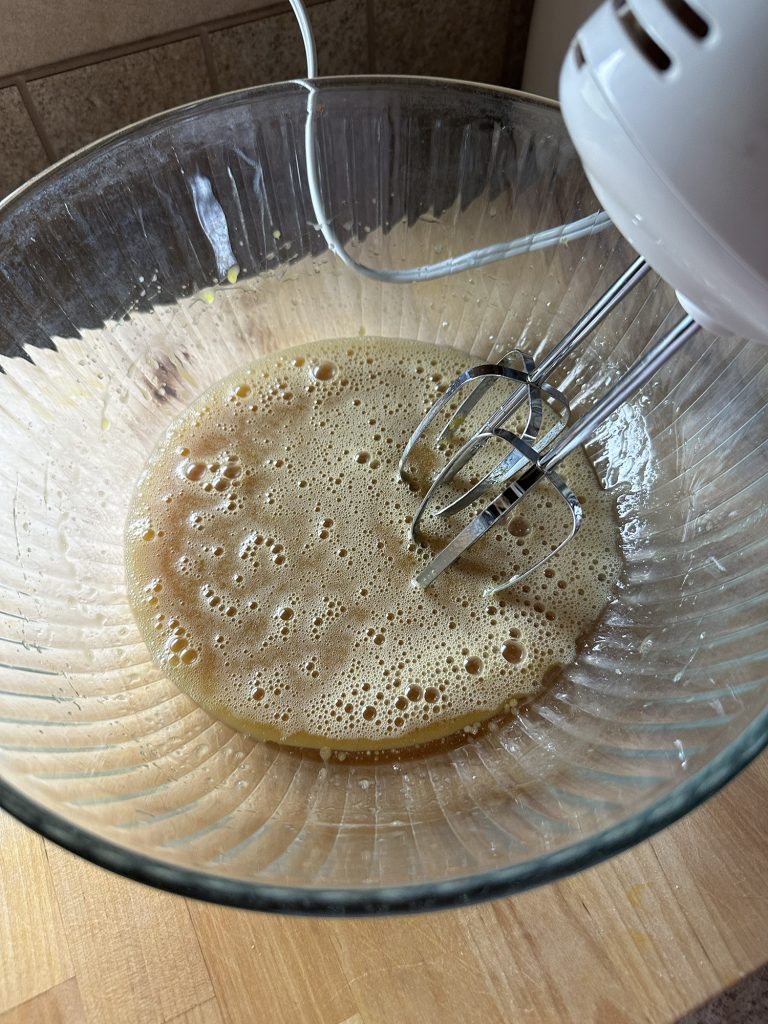 Ingredients for muffins in a bown being mixed with hand mixer