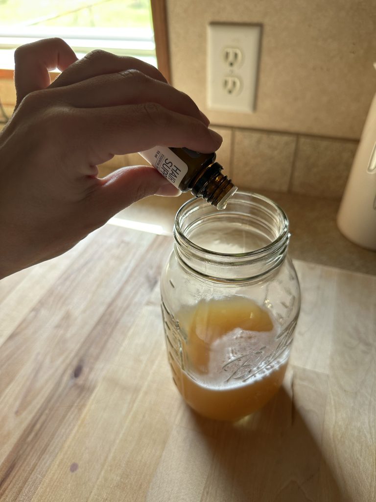 dropping essential oils into soap nut shampoo sitting on counter